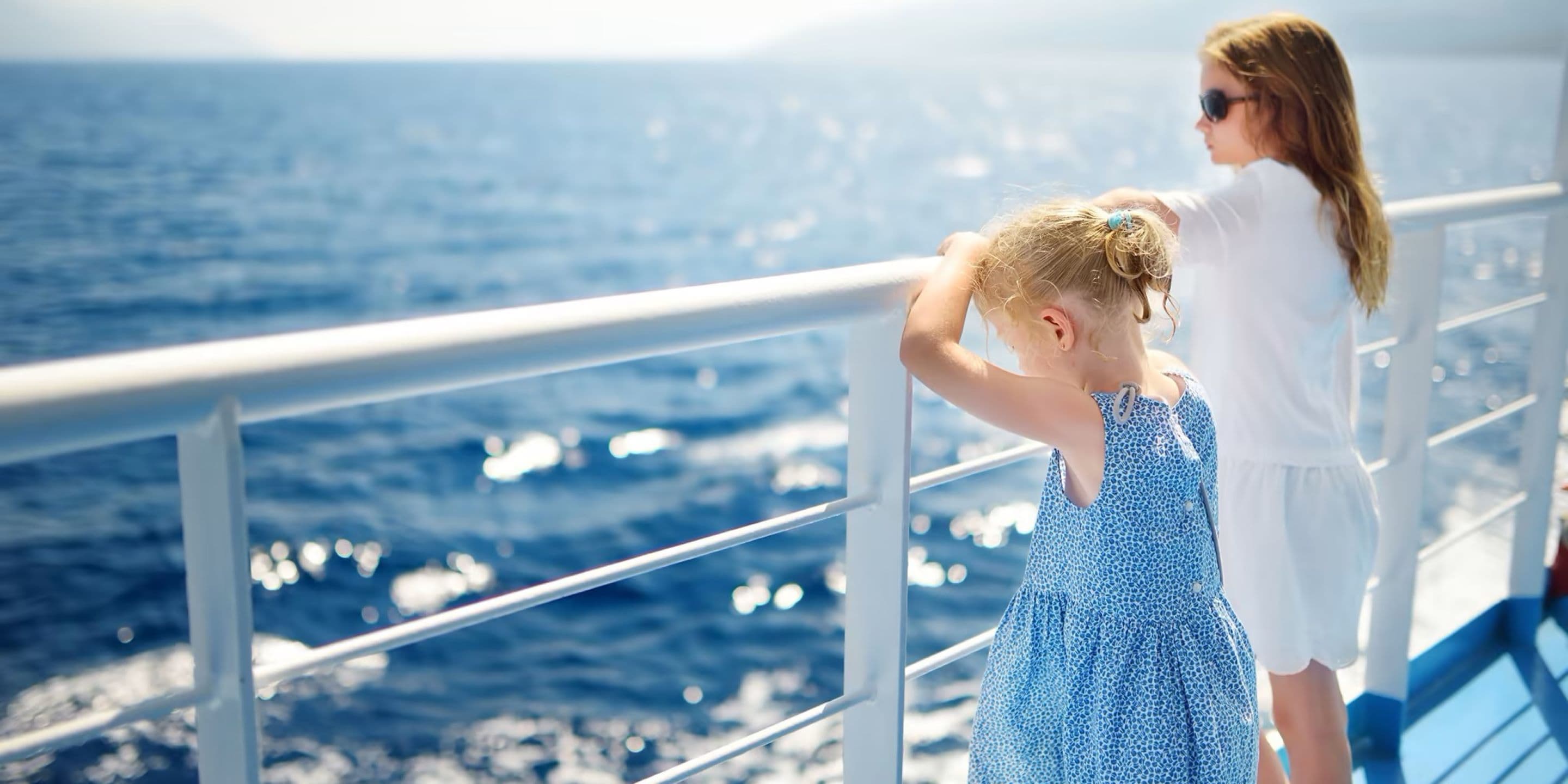 Onity two young girls looking over ship railing at the water