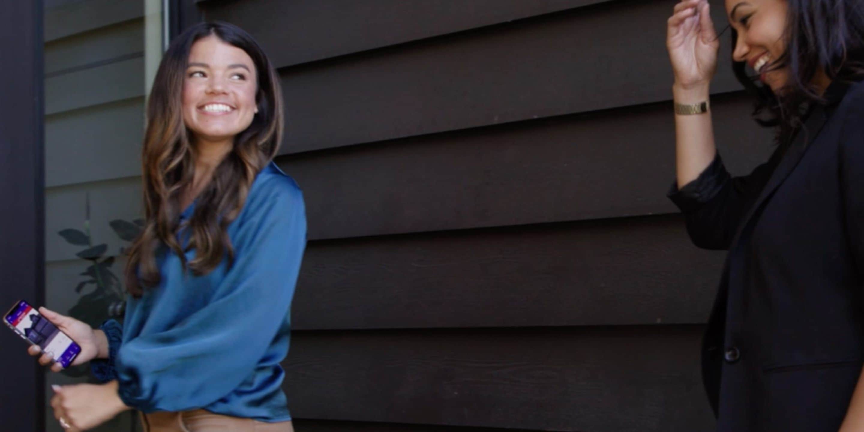 Young adult female real estate opening lockbox with ekey app for showing with female client