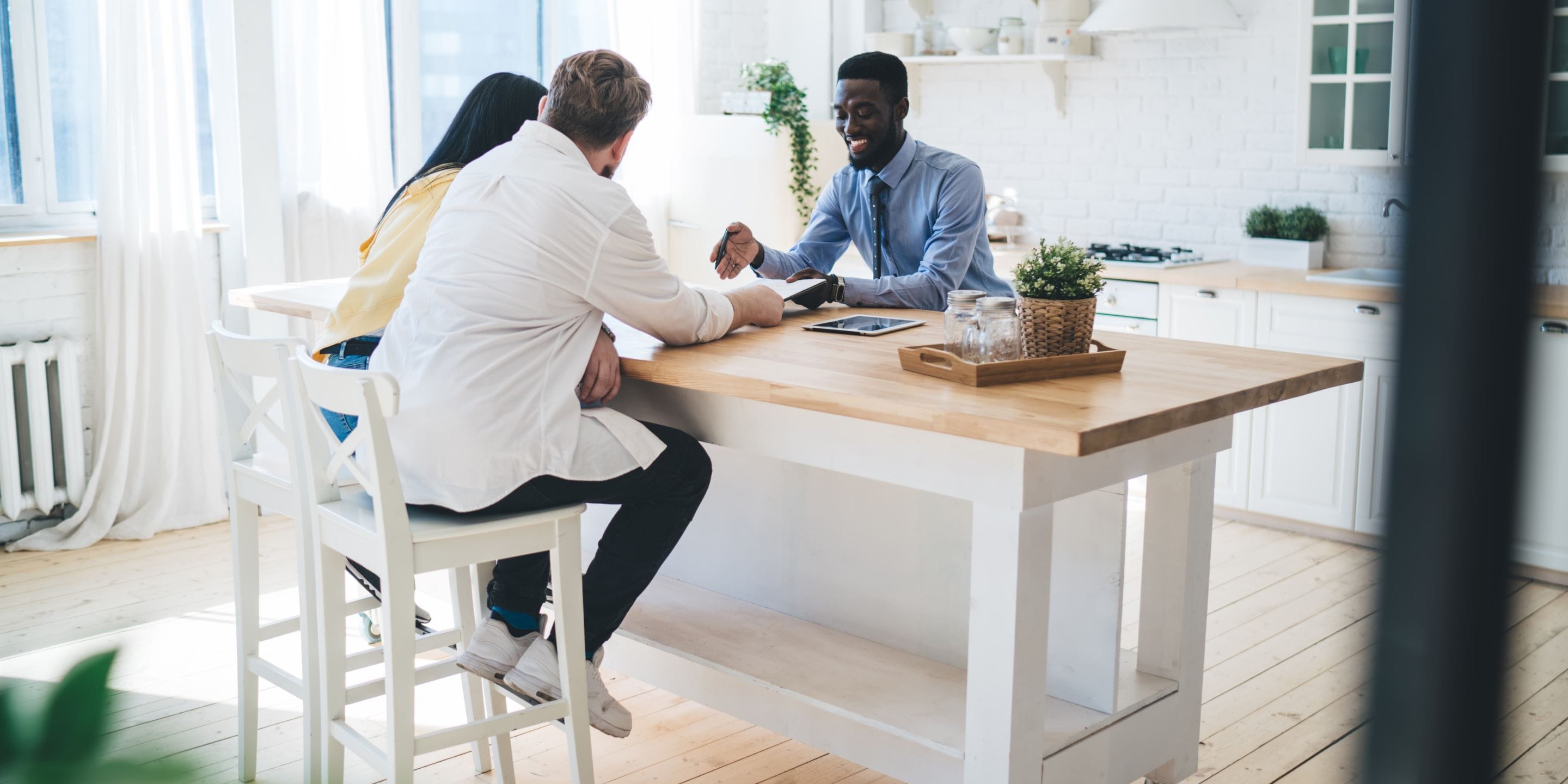 Real Estate Agent Sitting With Couple in Kitchen