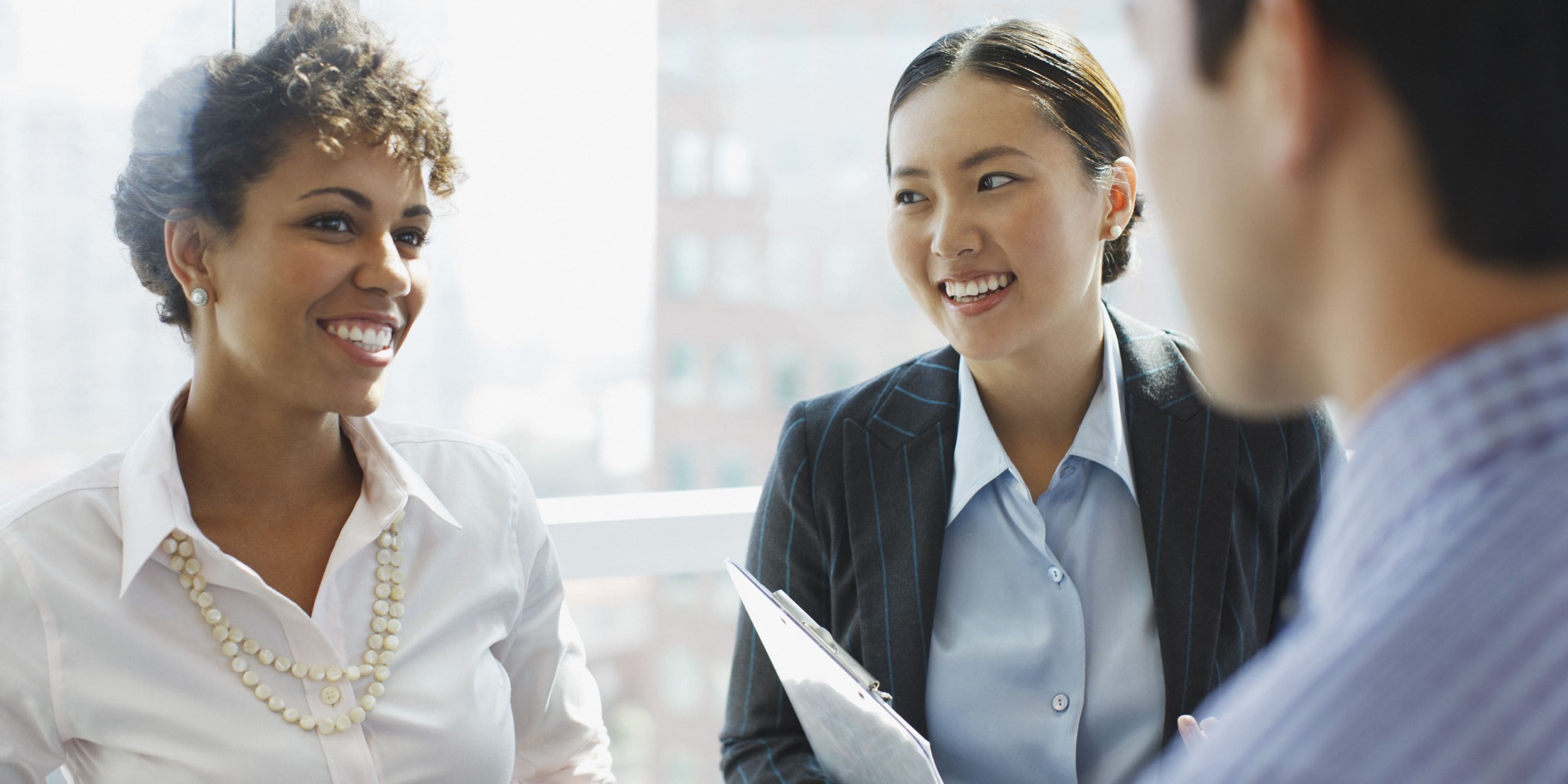 Three professionals in business attire chatting