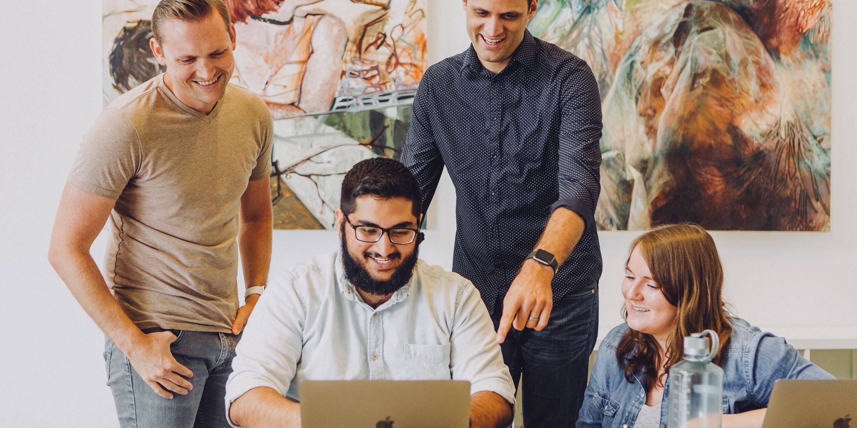 Young professionals gathered around looking at laptop