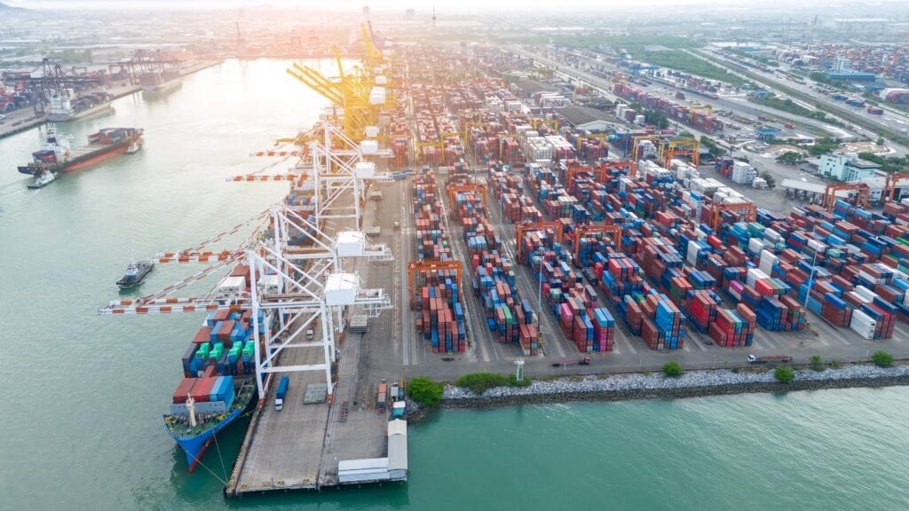Crane loading box container to cargo ship at commercial dock port. Shipyard Cargo Container Sea Port Freight forwarding service logistics and transportation. International Shipping Depot