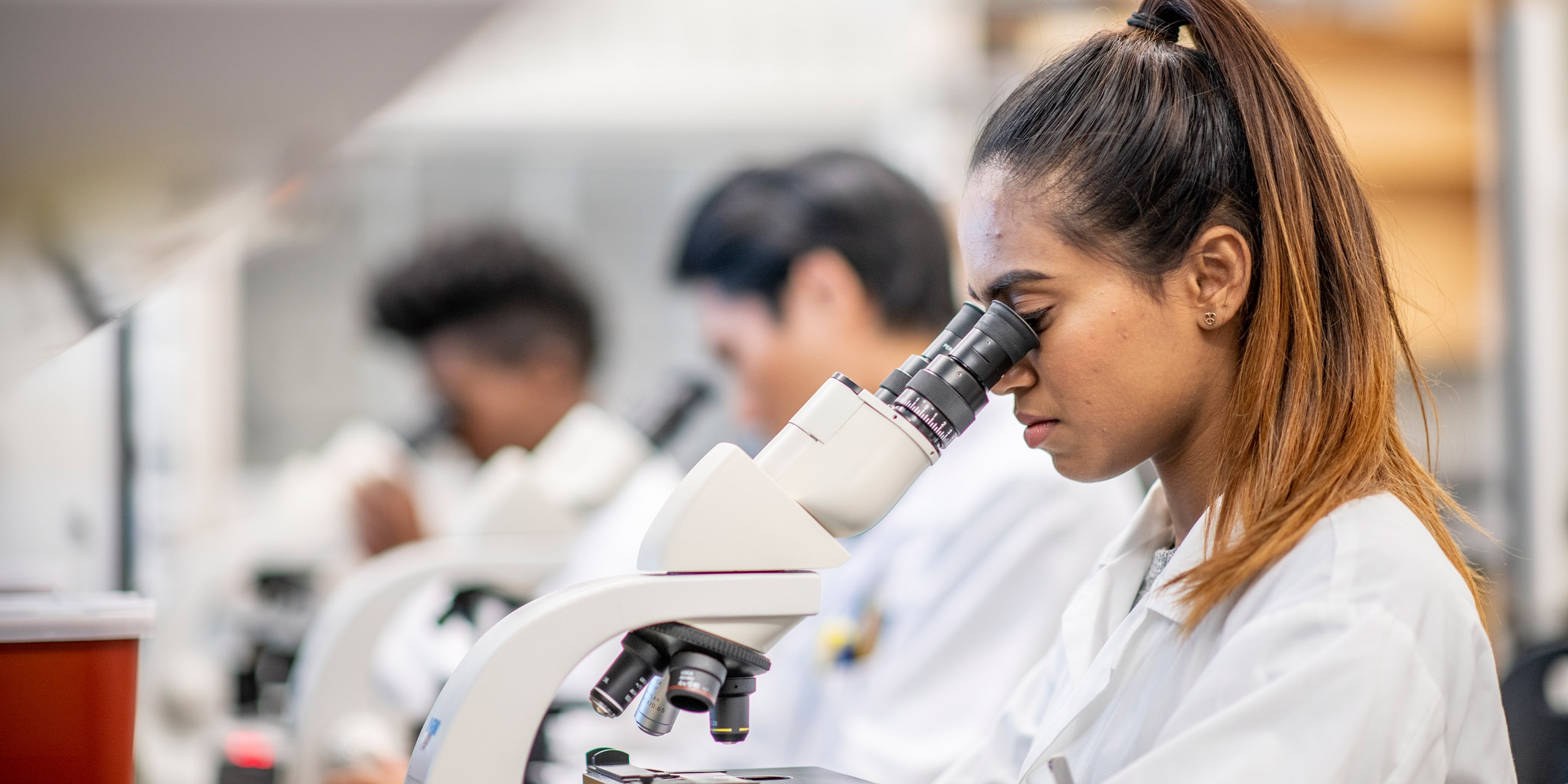 Woman looking in microscope in lab