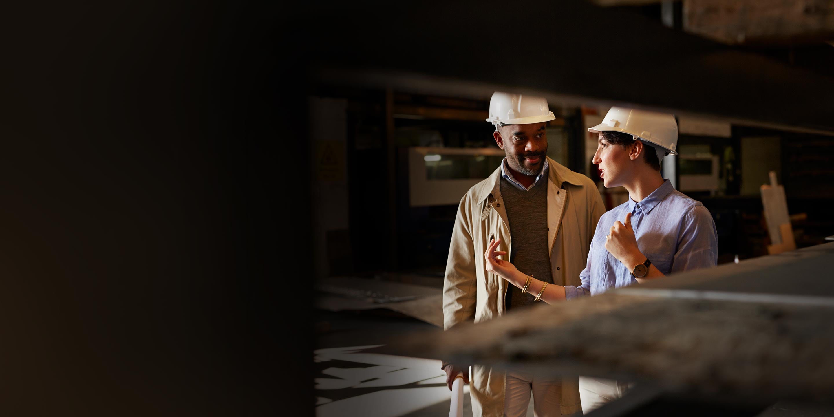 Two workers in hardhats talking in a construction site