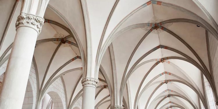 Explore the breathtaking architecture of a Gothic cathedral interior featuring intricate ribbed vaults, elegant columns, and detailed stone carvings. This image captures the grandeur and beauty of historical church design.
