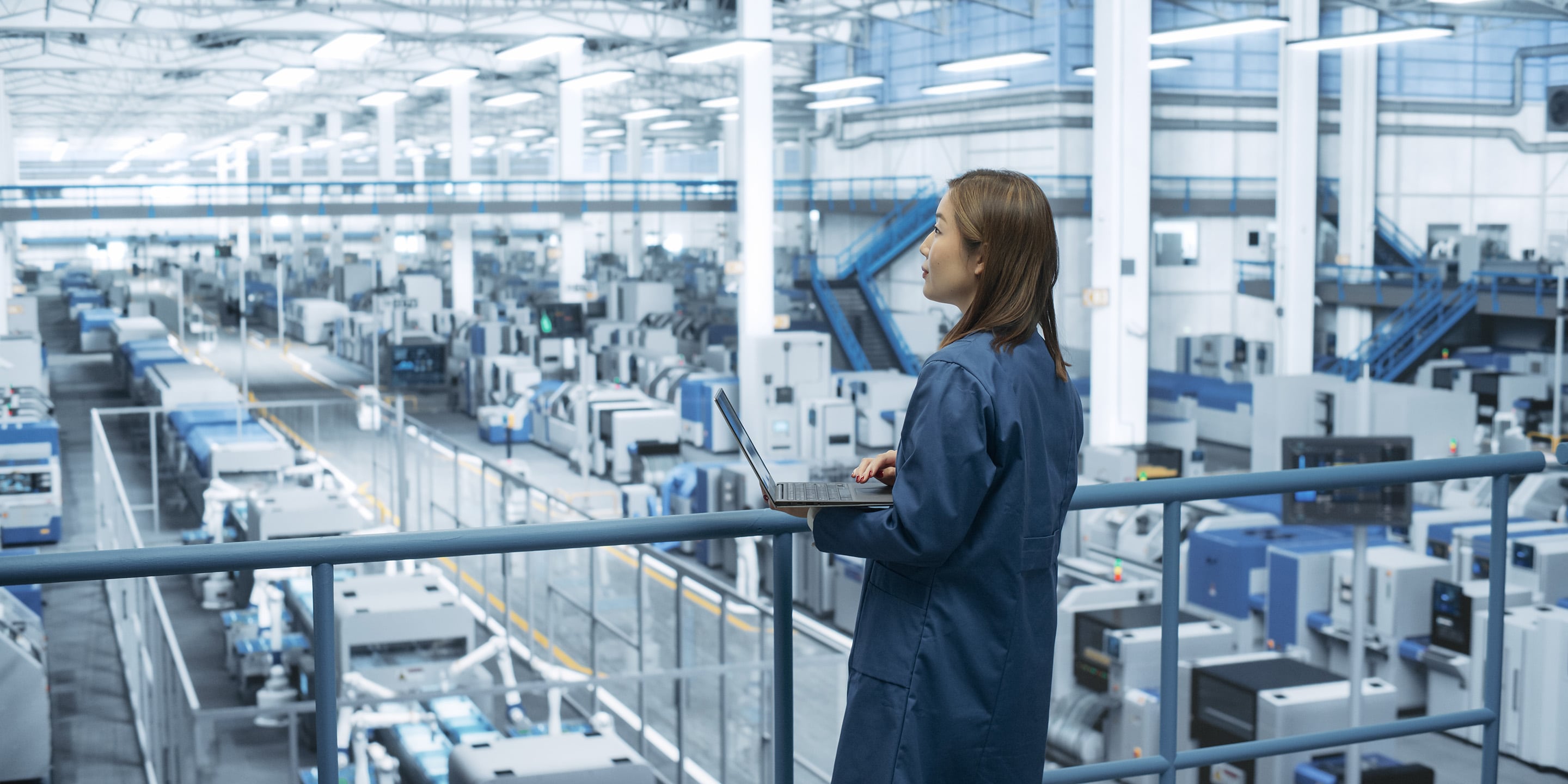 Manufacturing Engineer Overlooking Factory and Monitoring. In the background we can clearly see the devices and systems
